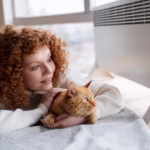 prone woman hugging a cat looking outside